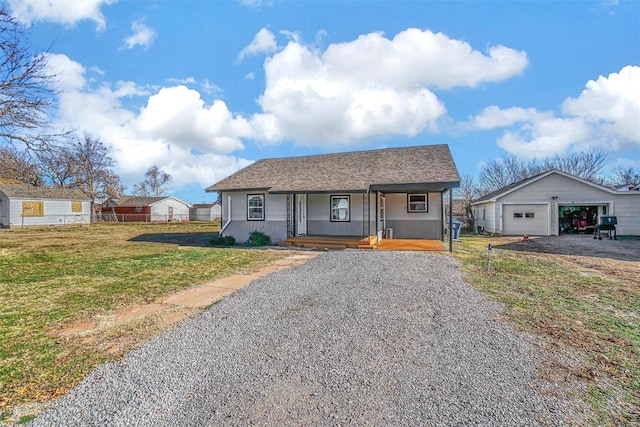 view of front of home featuring a garage, covered porch, an outbuilding, and a front yard