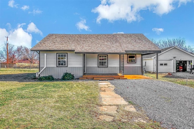 view of front of property featuring a garage, covered porch, an outbuilding, and a front lawn