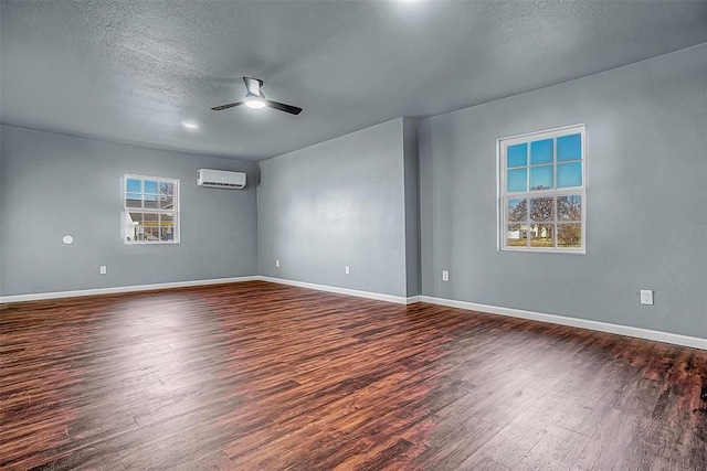 spare room featuring ceiling fan, a textured ceiling, a wall unit AC, and dark wood-type flooring