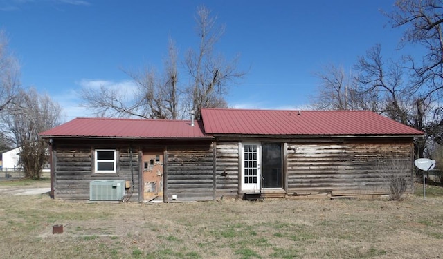 rear view of house with cooling unit and a yard