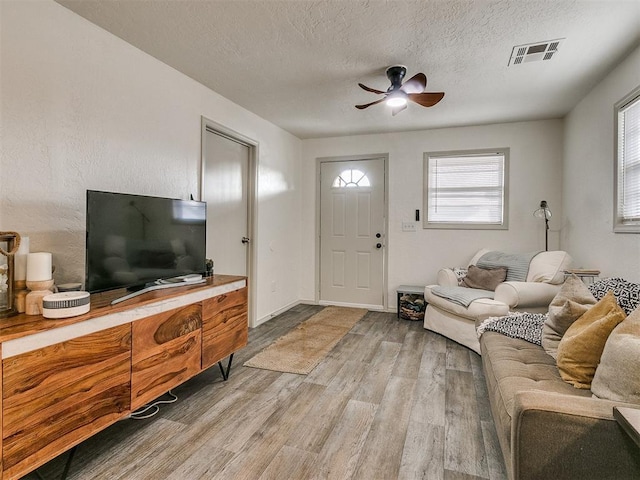 living room with ceiling fan, light hardwood / wood-style floors, and a textured ceiling