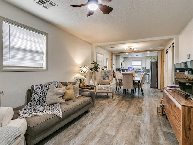 living room with ceiling fan, a textured ceiling, and hardwood / wood-style flooring