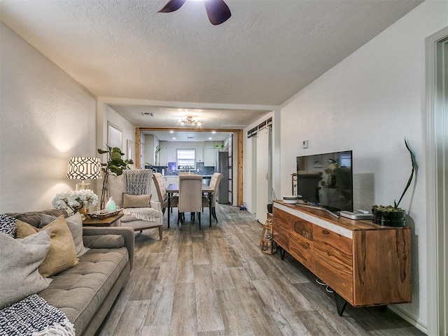 living room with ceiling fan, a textured ceiling, and hardwood / wood-style flooring