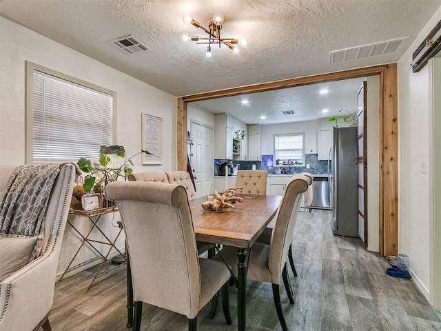 dining room with hardwood / wood-style floors, a textured ceiling, and a chandelier