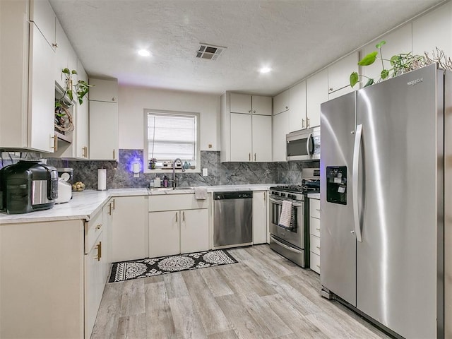 kitchen featuring white cabinets, appliances with stainless steel finishes, light hardwood / wood-style flooring, and sink