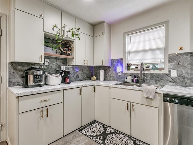 kitchen featuring white cabinetry, dishwasher, sink, light hardwood / wood-style flooring, and backsplash