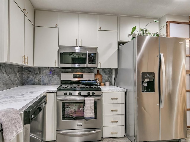 kitchen with appliances with stainless steel finishes, backsplash, white cabinetry, and light stone counters