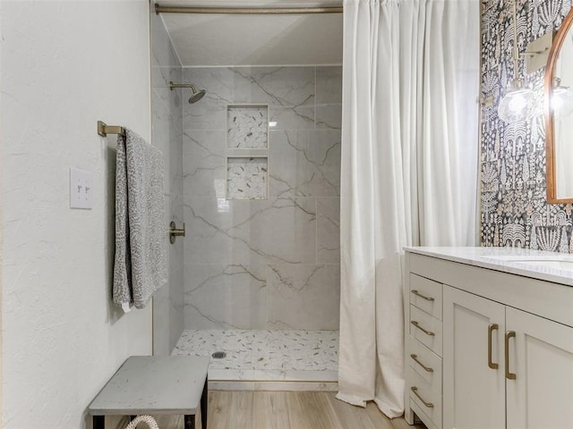 bathroom with vanity, a marble finish shower, and wood finished floors