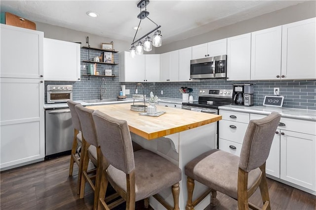 kitchen with sink, stainless steel appliances, a kitchen island, dark hardwood / wood-style floors, and white cabinets