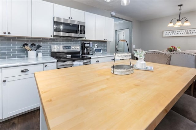 kitchen with butcher block countertops, decorative light fixtures, white cabinetry, and stainless steel appliances