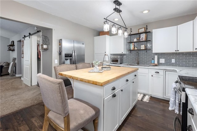 kitchen featuring a center island, sink, a barn door, white cabinetry, and stainless steel appliances