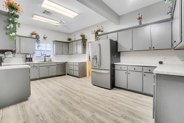 kitchen featuring stainless steel appliances, gray cabinets, ceiling fan, and light hardwood / wood-style floors