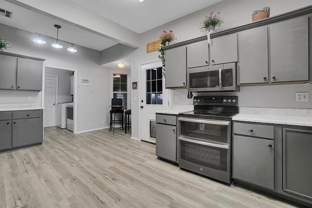 kitchen featuring gray cabinetry, stainless steel appliances, decorative light fixtures, and light wood-type flooring