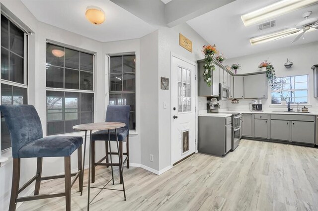 kitchen with gray cabinets, sink, stainless steel appliances, and light hardwood / wood-style flooring