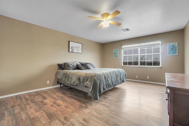 bedroom featuring ceiling fan, light wood-type flooring, and a textured ceiling