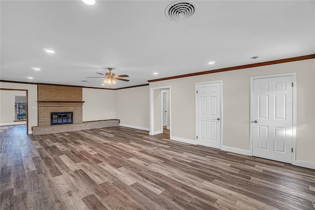 unfurnished living room featuring ceiling fan, a fireplace, wood-type flooring, and ornamental molding