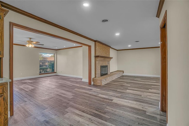 unfurnished living room featuring ceiling fan, light wood-type flooring, a fireplace, and ornamental molding