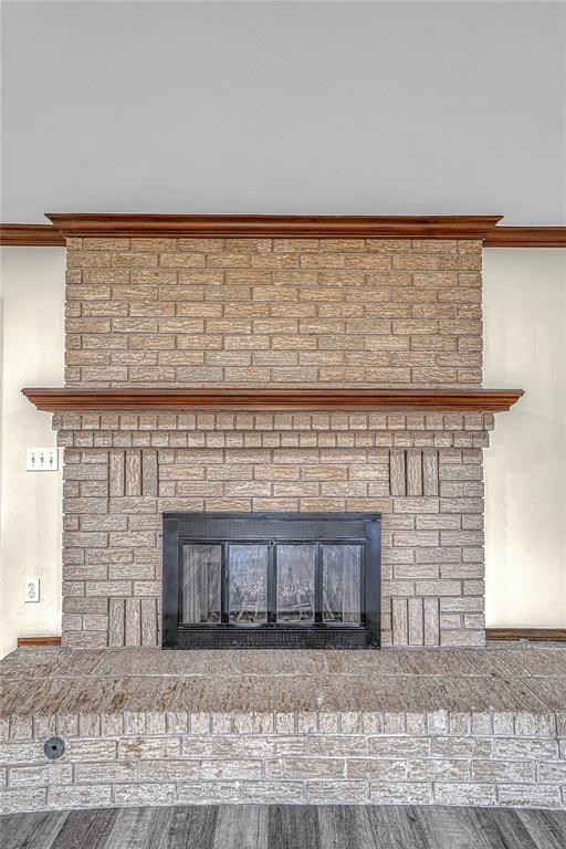 interior details featuring hardwood / wood-style floors, ornamental molding, and a brick fireplace