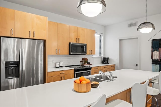 kitchen with light brown cabinets, backsplash, a breakfast bar area, decorative light fixtures, and stainless steel appliances