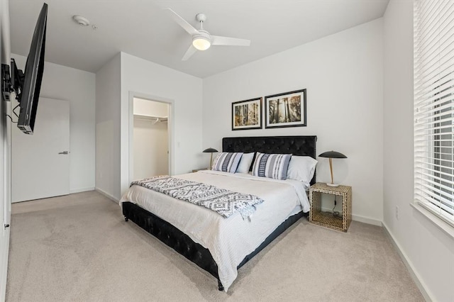 carpeted bedroom with a walk in closet, a closet, and ceiling fan