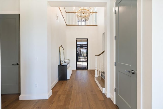 foyer entrance featuring a chandelier, hardwood / wood-style floors, and a high ceiling