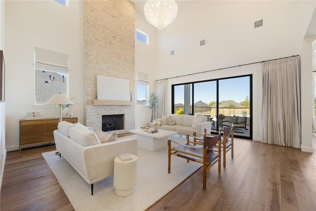 living room featuring a fireplace, a high ceiling, hardwood / wood-style flooring, and a chandelier