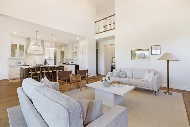 living room featuring light wood-type flooring and a towering ceiling