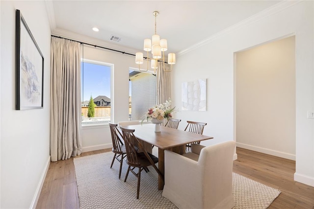 dining room with an inviting chandelier, ornamental molding, and hardwood / wood-style flooring