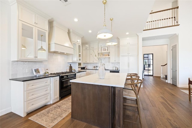 kitchen featuring pendant lighting, custom exhaust hood, high end stove, and dark wood-type flooring