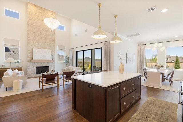 kitchen with a stone fireplace, hanging light fixtures, dark hardwood / wood-style floors, and an inviting chandelier