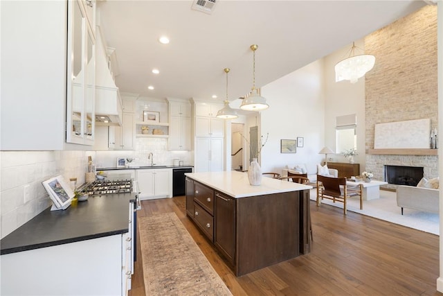 kitchen featuring dark brown cabinets, a center island, dark wood-type flooring, black dishwasher, and hanging light fixtures