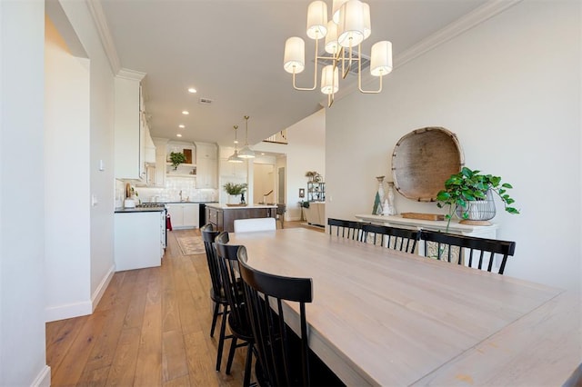 dining space with crown molding, light hardwood / wood-style flooring, and a notable chandelier