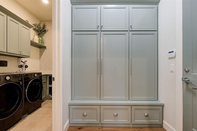 laundry room featuring cabinets, independent washer and dryer, and light wood-type flooring