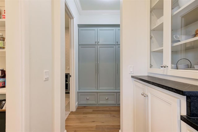 bar featuring gray cabinetry, crown molding, dark stone counters, and light wood-type flooring