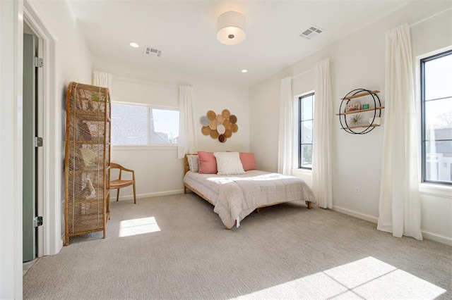 bedroom with light colored carpet and multiple windows