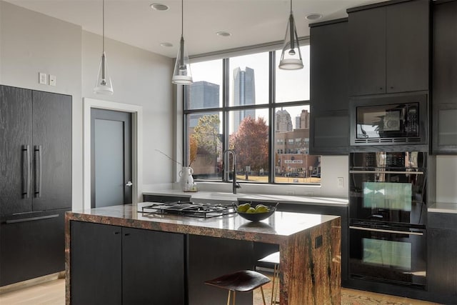 kitchen featuring black appliances, a center island, pendant lighting, and dark stone countertops