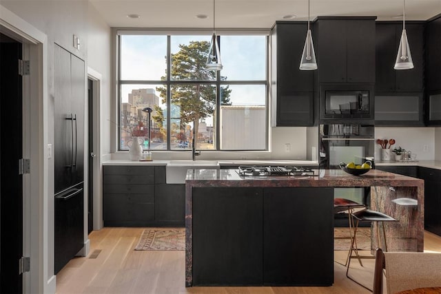 kitchen with a center island, black appliances, decorative light fixtures, and light hardwood / wood-style flooring