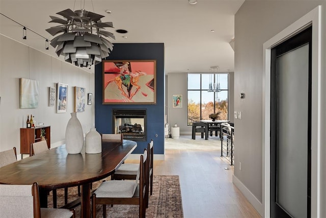 dining area featuring a multi sided fireplace, light hardwood / wood-style flooring, and ceiling fan