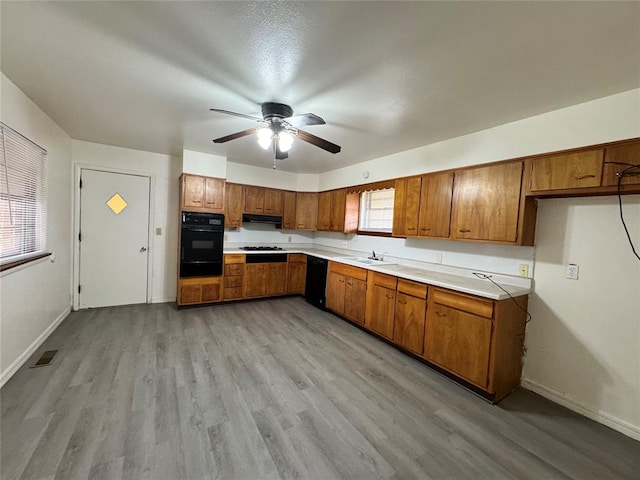 kitchen featuring black appliances, ventilation hood, sink, light hardwood / wood-style flooring, and ceiling fan