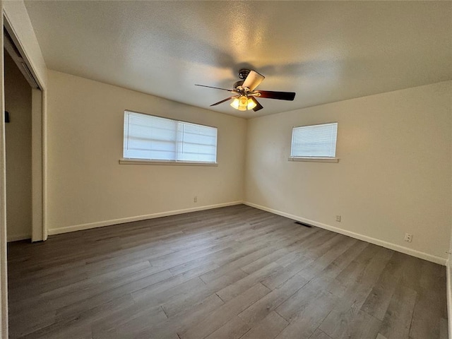 unfurnished bedroom with a textured ceiling, ceiling fan, dark wood-type flooring, and a closet