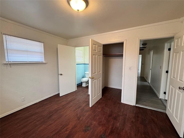 unfurnished bedroom with ensuite bathroom, dark hardwood / wood-style flooring, ornamental molding, and a closet