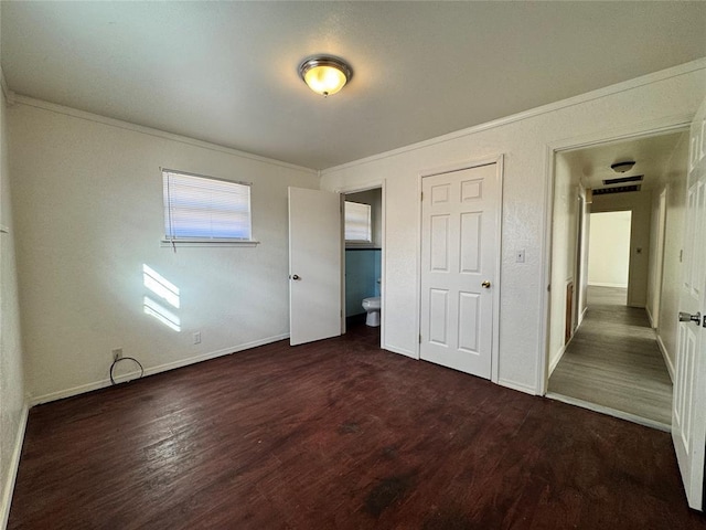 unfurnished bedroom with dark hardwood / wood-style floors, crown molding, and ensuite bath