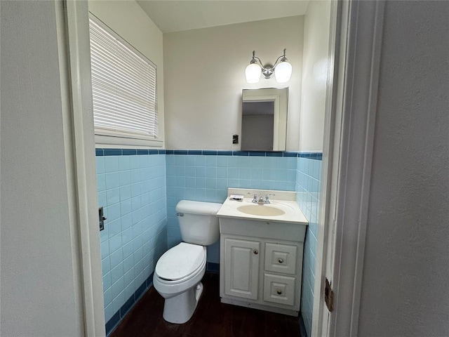 bathroom featuring hardwood / wood-style flooring, vanity, toilet, and tile walls