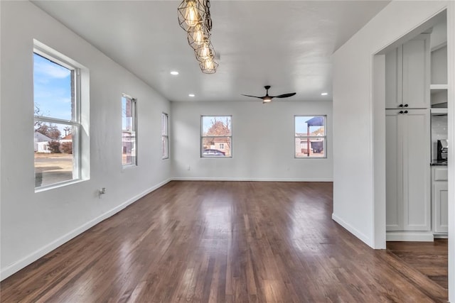 unfurnished living room featuring ceiling fan, plenty of natural light, and dark hardwood / wood-style floors