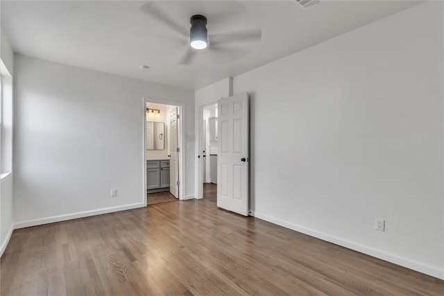 unfurnished bedroom featuring hardwood / wood-style floors, ceiling fan, and ensuite bathroom