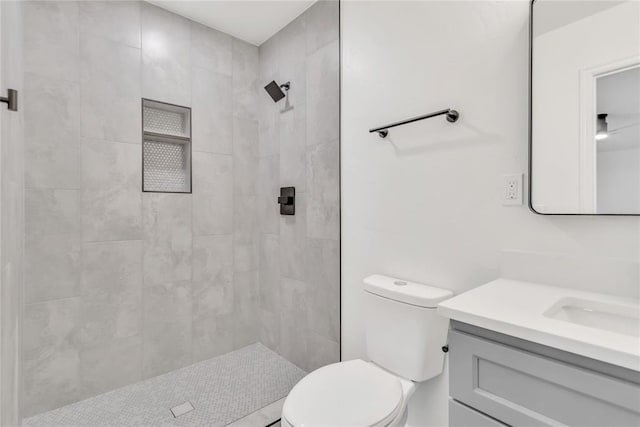 bathroom with vanity, toilet, and a tile shower