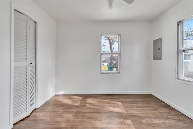 unfurnished bedroom featuring electric panel, ceiling fan, and hardwood / wood-style flooring