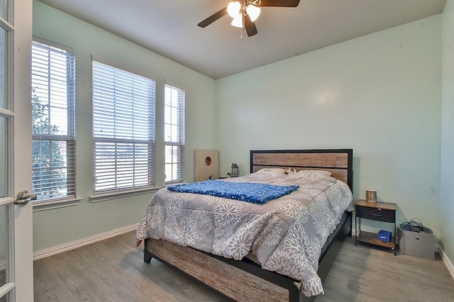 bedroom featuring hardwood / wood-style floors, ceiling fan, and multiple windows