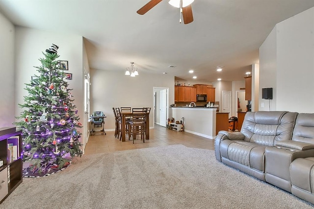 tiled living room with ceiling fan with notable chandelier