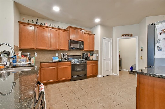 kitchen with light tile patterned floors, sink, dark stone countertops, and black appliances